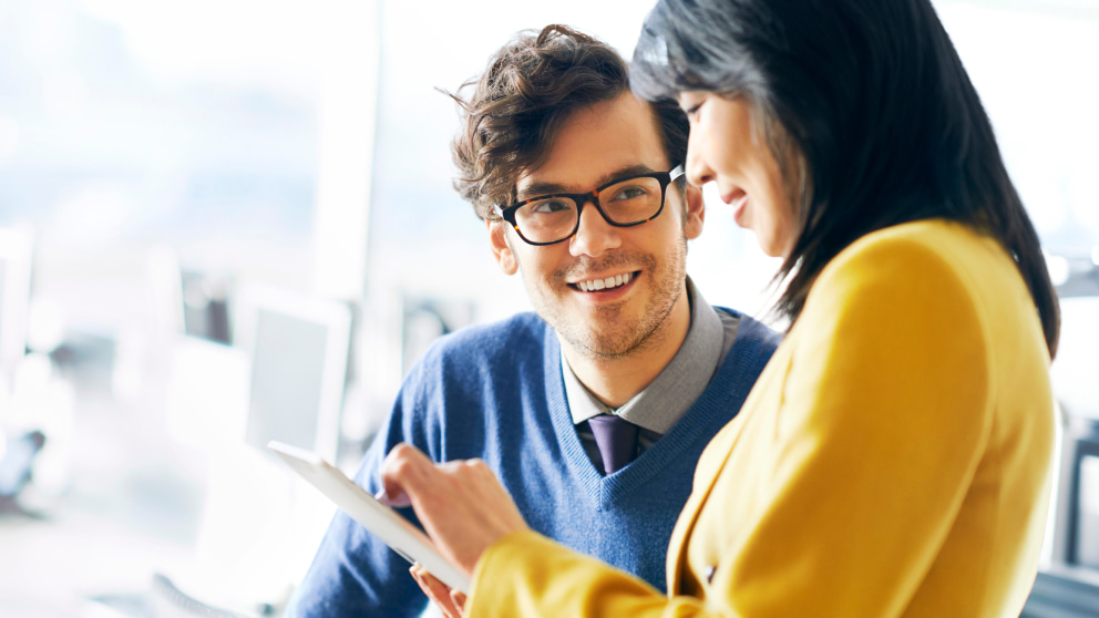 man and woman smiling at tablet